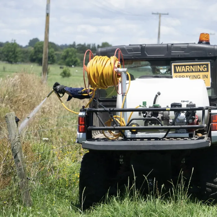 The Polaris ground rig with hose and reel spraying along a rural fence line