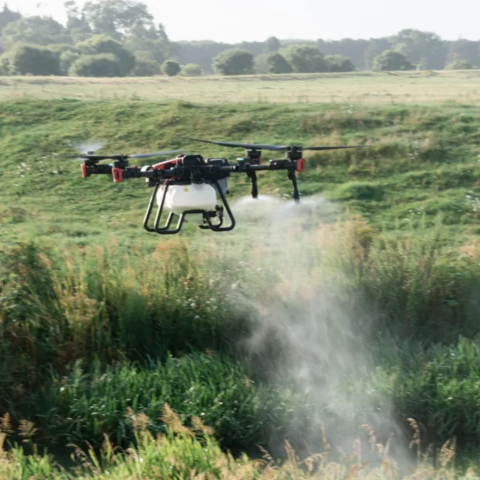A spray drone applying weed control over a grassy paddock edge